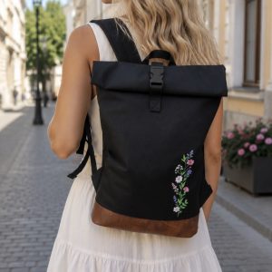 Rolovací batoh s výšivka lučních květů na černém podkladu.